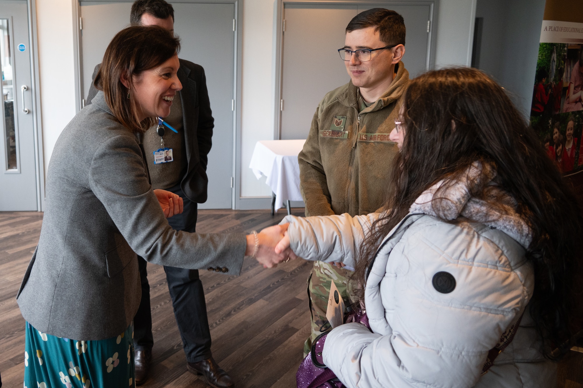 A pathfinder shakes the hand of a representative from a local school during a British school information fair