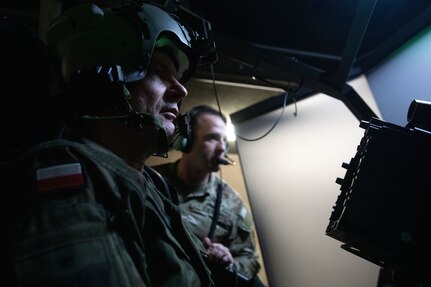 U.S. and Polish Armed Forces Soldiers simulate the flight of an AH-64Ev6 Apache Guardian, during the second Polish Apache Initiative summit at U.S. Army Garrison Ansbach, Germany, Jan 24, 2025. Hosted by the 12th Combat Aviation Brigade, the second Polish Apache Initiative summit provided the U.S., Poland, U.K., and Netherlands with an international forum for discussion on tactics, training, and maintenance of the AH-64Ev6 Apache Guardian Helicopter. (U.S. Army photo by Pfc. Jolene Cintron)