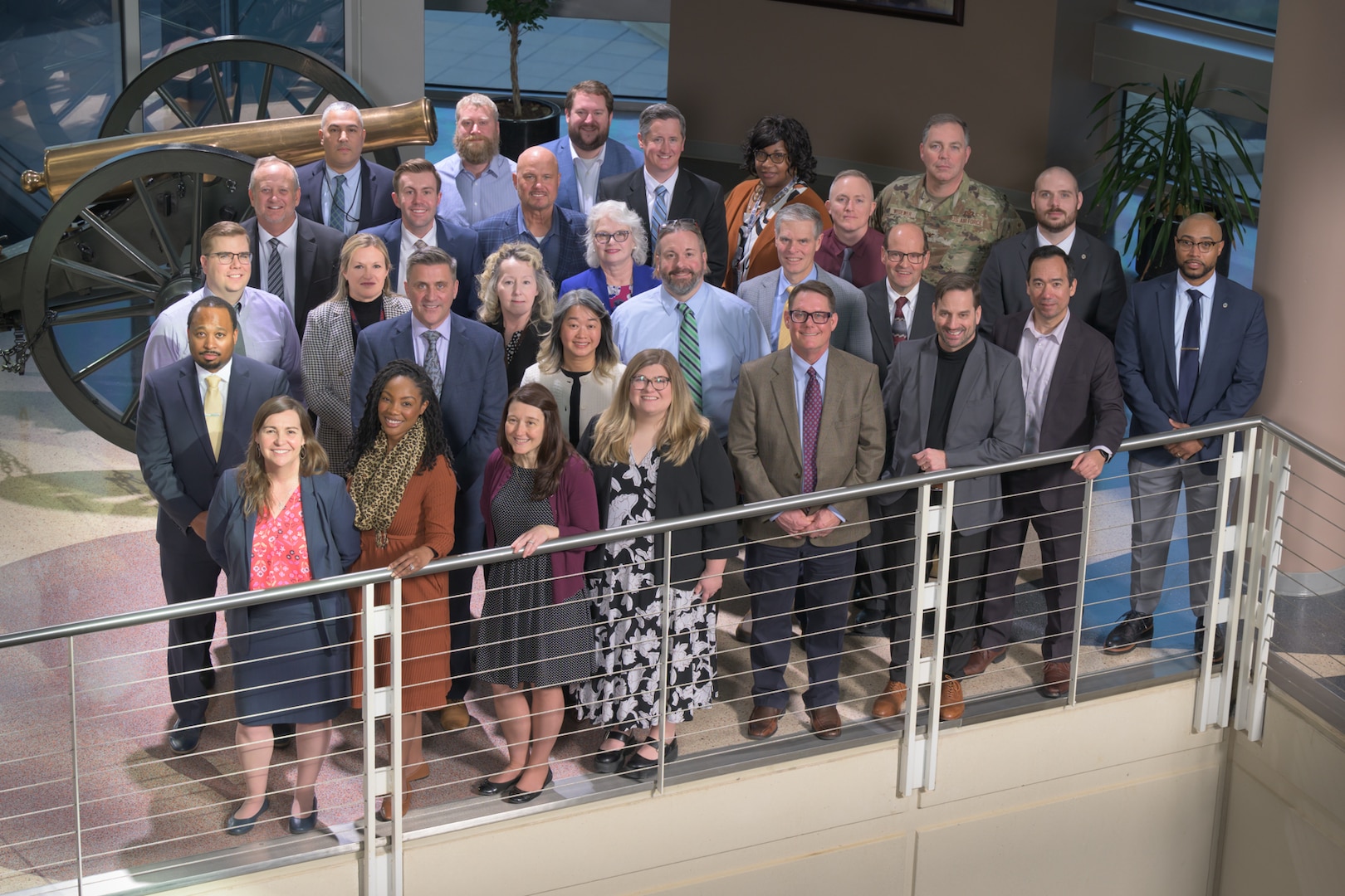 Almost 25 men and women stand near a railing
