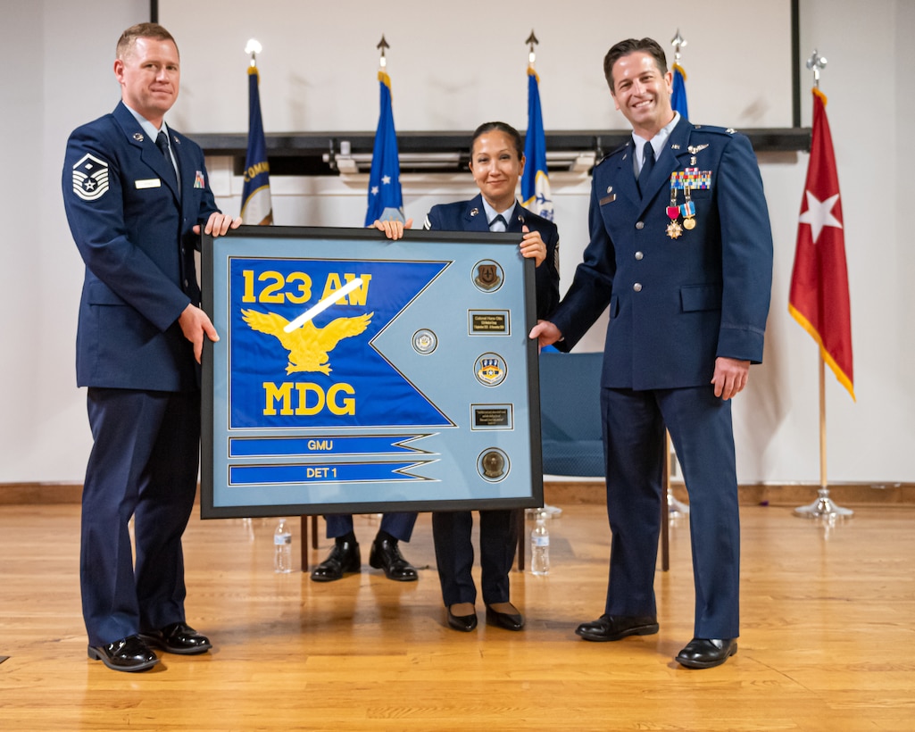 Airmen from the 123rd Medical Group present Col. Hans Otto, right, outgoing group commander, with a framed unit flag during his retirement ceremony at the Kentucky Air National Guard Base in Louisville, Ky., Dec. 15, 2024.