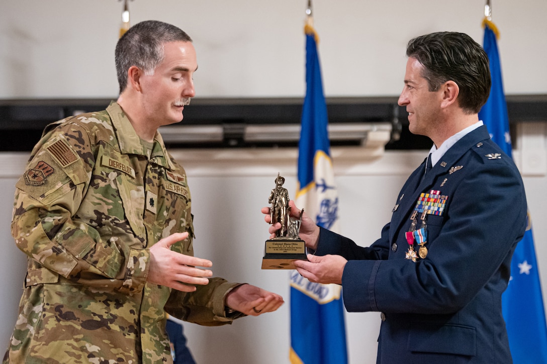 Lt. Col. Daniel Dierfeldt, left, chief of aerospace medicine for the 123rd Medical Group, presents Col. Hans Otto, outgoing group commander, with a Minuteman statue during Otto’s retirement ceremony at the Kentucky Air National Guard Base in Louisville, Ky., Dec. 15, 2024.