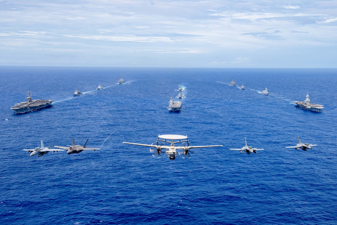 Aircraft from the Carl Vinson Carrier Strike Group (VINCSG) and French Carrier Strike Group (CSG) fly in formation over the Philippine Sea with ships from VINCSG, French CSG, the Japan Maritime Self-Defense Force (JMSDF), and U.S. Military Sealift Command (MSC) during Pacific Steller 2025.