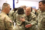 Guardsmen hug one another and shake hands indoors.