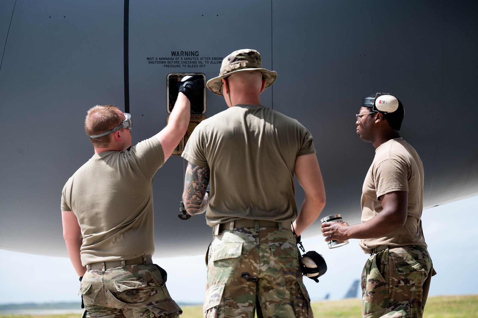 Three airmen check the engine oil of a KC-135R Stratotanker aircraft.