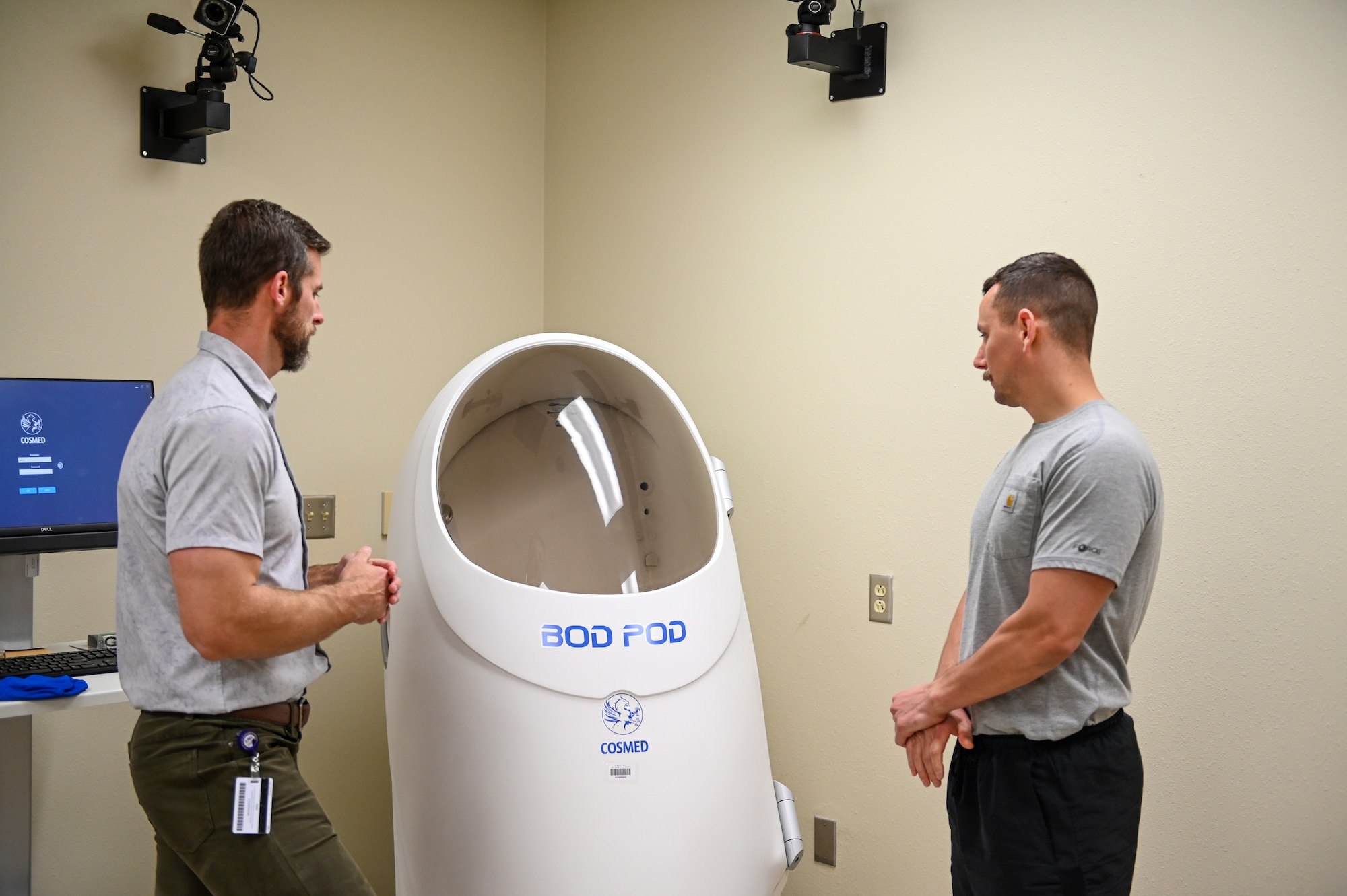 Two men look at a body composition measuring tool, otherwise referred to as the Bod Pod.