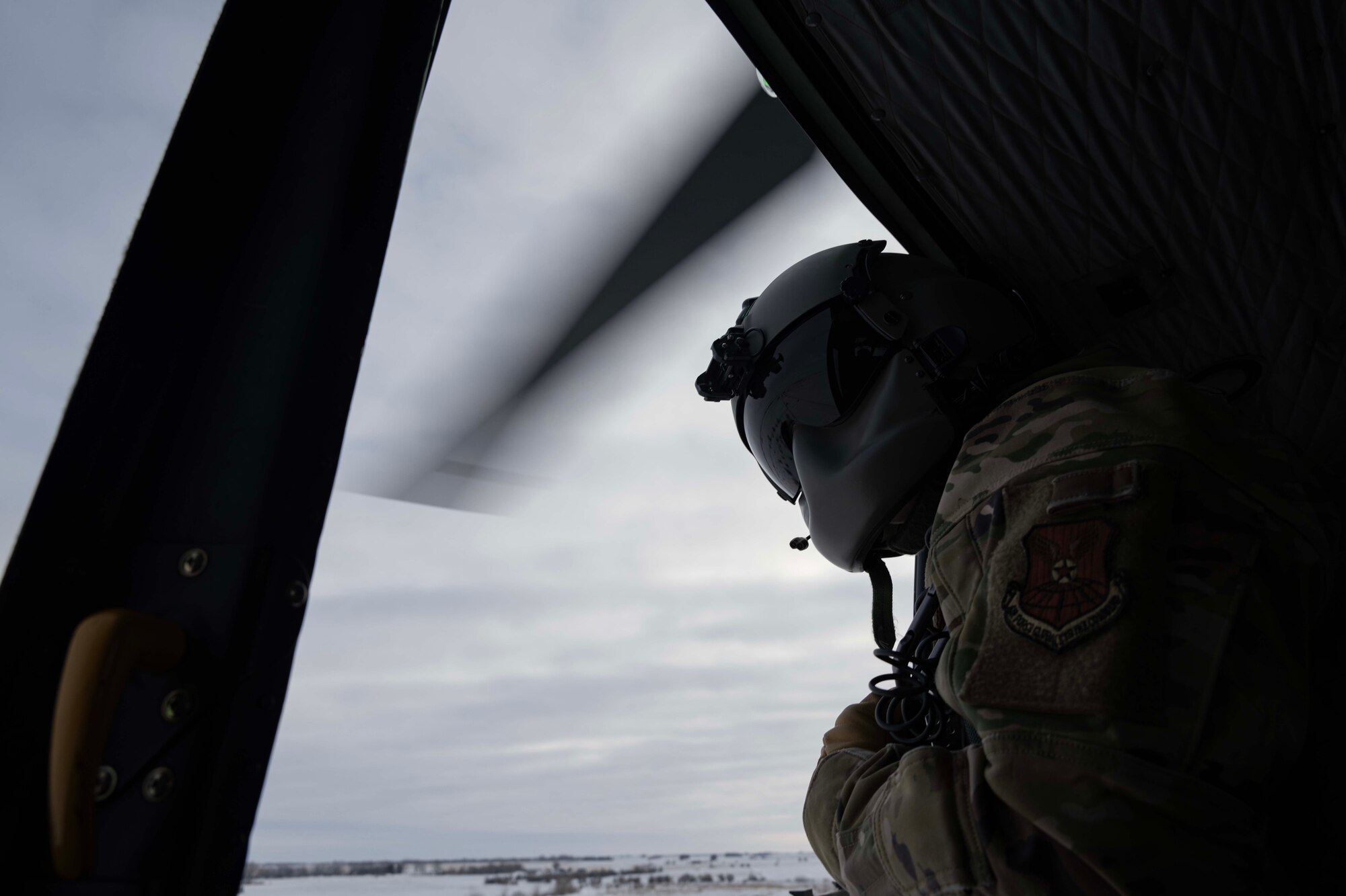 U.S. Air Force Staff Sgt. Garrett Hightower, 54th Helicopter Squadron flight engineer, looks out of a UH-1N Iroquois during a flight at Minot Air Force Base, North Dakota, Feb. 7, 2025. Based on the phonetic sound of its initial designation, HU-1, the UH-1 is referred to as a "Huey." (U.S. Air Force photo by Senior Airman Alyssa Bankston)