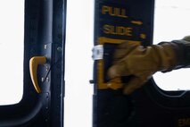 U.S. Air Force Staff Sgt. Garrett Hightower, 54th Helicopter Squadron flight engineer, opens the door of a UH-1N Iroquois at Minot Air Force Base, North Dakota, Feb. 7, 2025. Based on the phonetic sound of its initial designation, HU-1, the UH-1 is referred to as a "Huey." (U.S. Air Force photo by Senior Airman Alyssa Bankston)