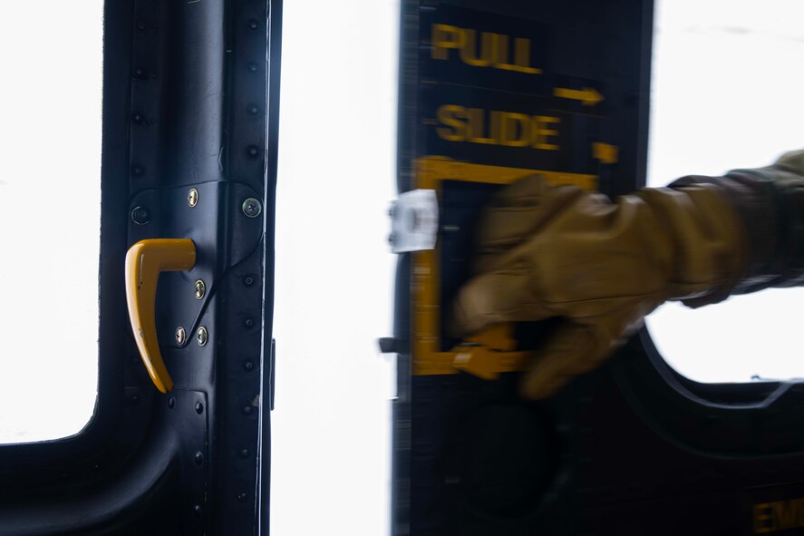 U.S. Air Force Staff Sgt. Garrett Hightower, 54th Helicopter Squadron flight engineer, opens the door of a UH-1N Iroquois at Minot Air Force Base, North Dakota, Feb. 7, 2025. Based on the phonetic sound of its initial designation, HU-1, the UH-1 is referred to as a "Huey." (U.S. Air Force photo by Senior Airman Alyssa Bankston)
