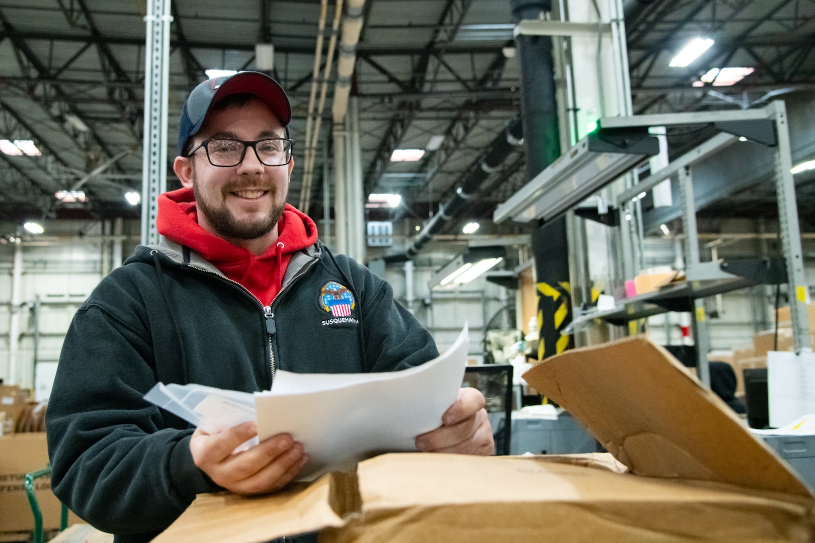 Photo is of a man in a warehouse with paperwork in his hand.