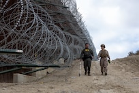 CBP agent and U.S. Marine measure area along southern border wall near San Ysidro, California