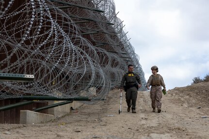 CBP agent and U.S. Marine measure area along southern border wall near San Ysidro, California