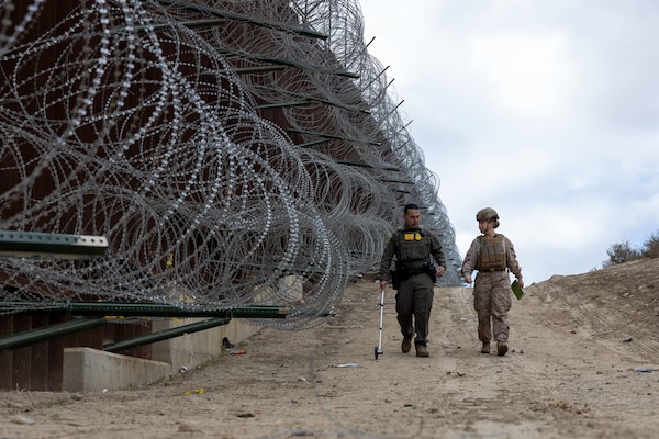 CBP agent and U.S. Marine measure area along southern border wall near San Ysidro, California