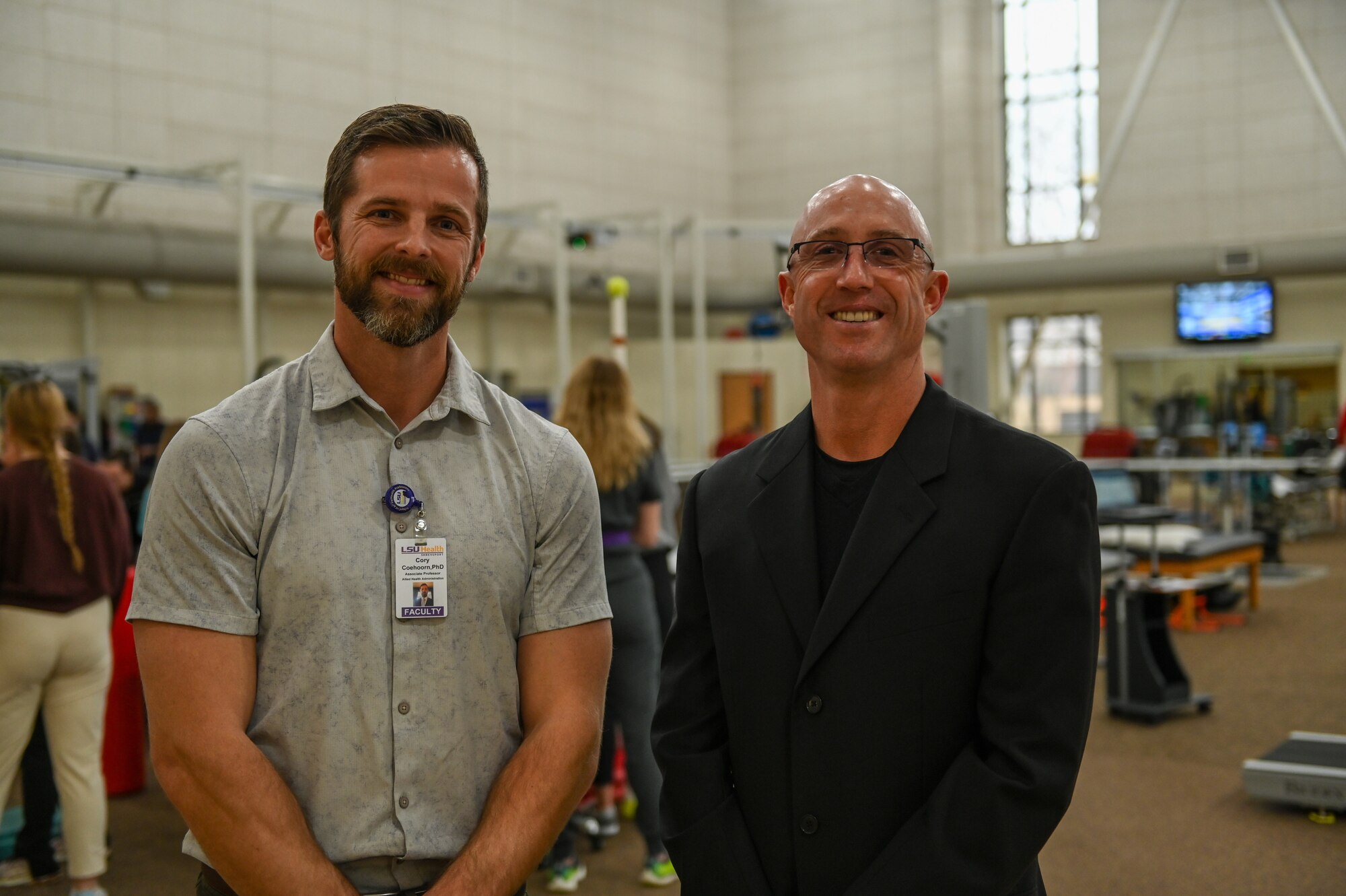 Two men stand together for a posed photo at a physical therapy clinic.
