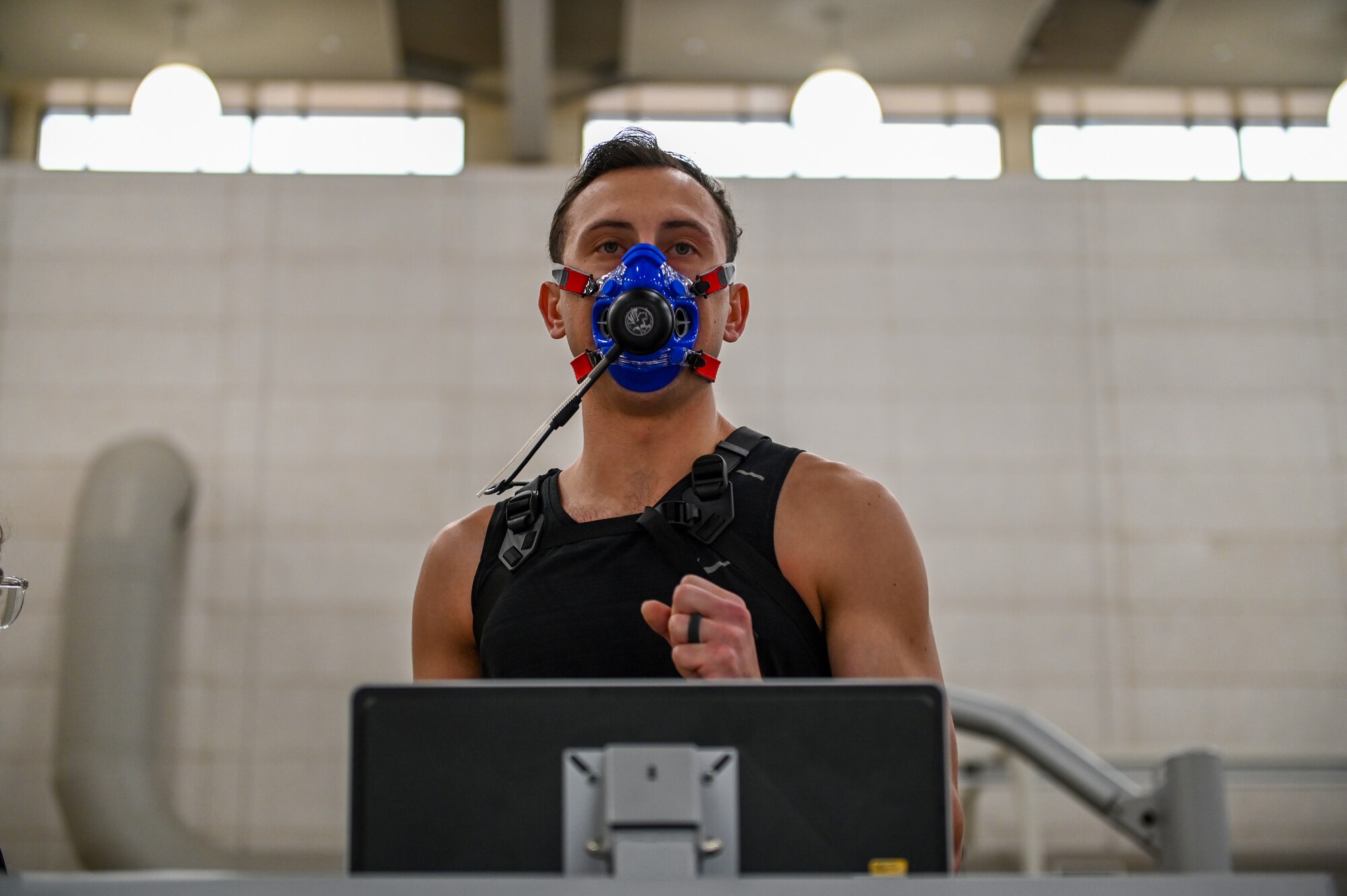 A man runs on a treadmill with a mask on that measures his oxygen intake.