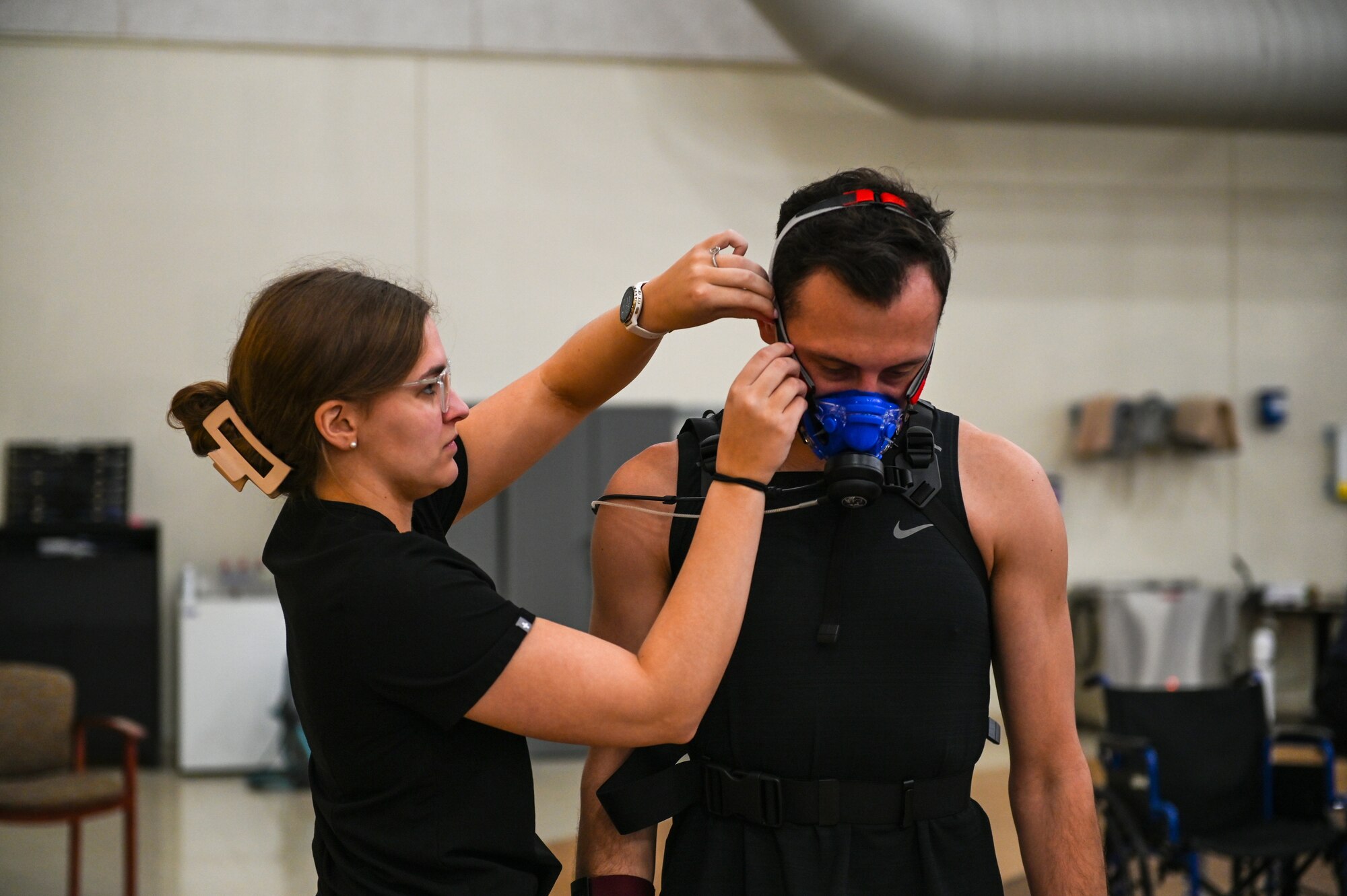 A medical student adjusts a man's face mask used to measure his oxygen intake.