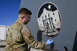 Senior Airman Nathen Willms, a 433rd Maintenance Squadron aircraft structural maintenance technician, applies a new logo to a 433rd Airlift Wing C- 5M Super Galaxy on Feb. 1, 2025, at Joint Base San Antonio-Lackland, Texas.