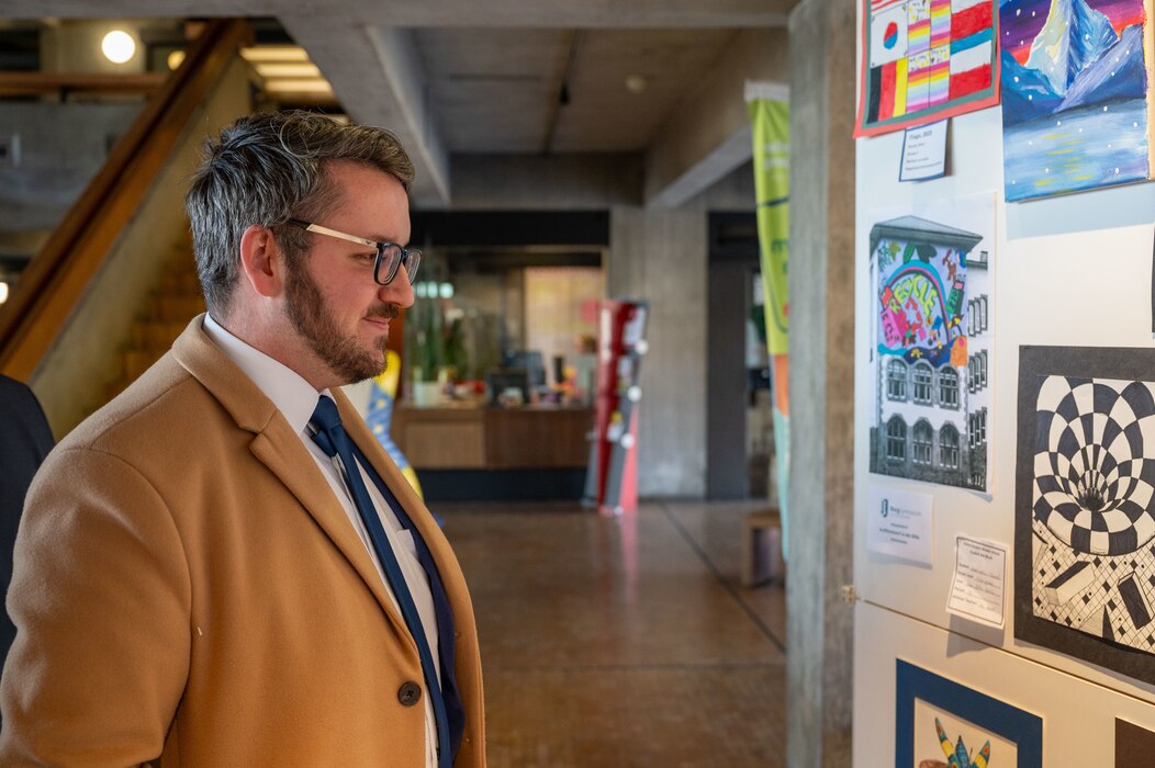 Jannik Ehlert, 86th Airlift Wing Host Nation advisor, admires artwork at a KMC student art exhibit opening for the 22nd German American Community Office anniversary in Kaiserslautern, Germany, Feb. 18, 2025. The Kottenschule, Burggymnasium, Vogelweh Elementary School, Kaiserslautern and Ramstein Middle School presented 20 pieces of artwork for the exhibition, showcasing the ongoing partnership between the military community and host nation.