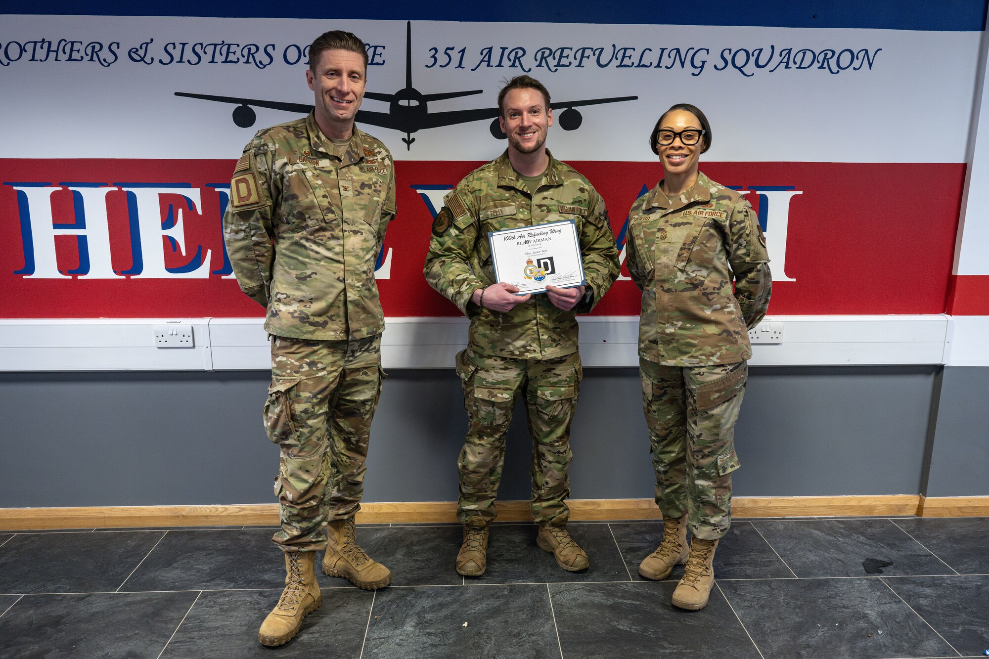 U.S. Air Force Staff Sgt. Justin Felix, center, 351st Air Refueling Squadron independent duty medical technician, receives the ReaDy Airman of the week award from Col. Ryan Garlow, left, 100th Air Refueling Wing commander, and Chief Master Sgt. Tiffany Griego, 100th ARW command chief, at RAF Mildenhall, England, Feb. 19, 2025.
