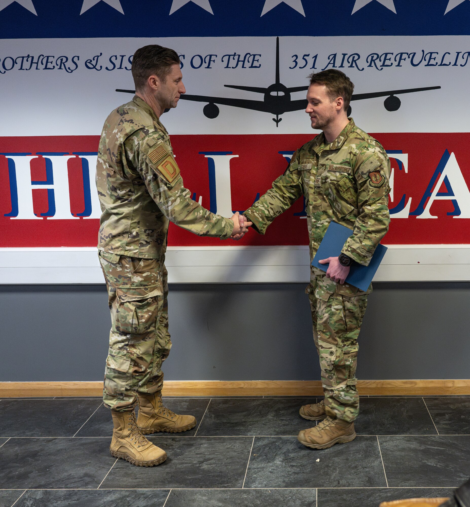 U.S. Air Force Col. Ryan Garlow, left, 100th Air Refueling Wing commander, shakes hands with Staff Sgt. Justin Felix, 351st Air Refueling Squadron independent duty medical technician, recognizing him as the ReaDy Airman of the Week at RAF Mildenhall, England, Feb. 19, 2025.