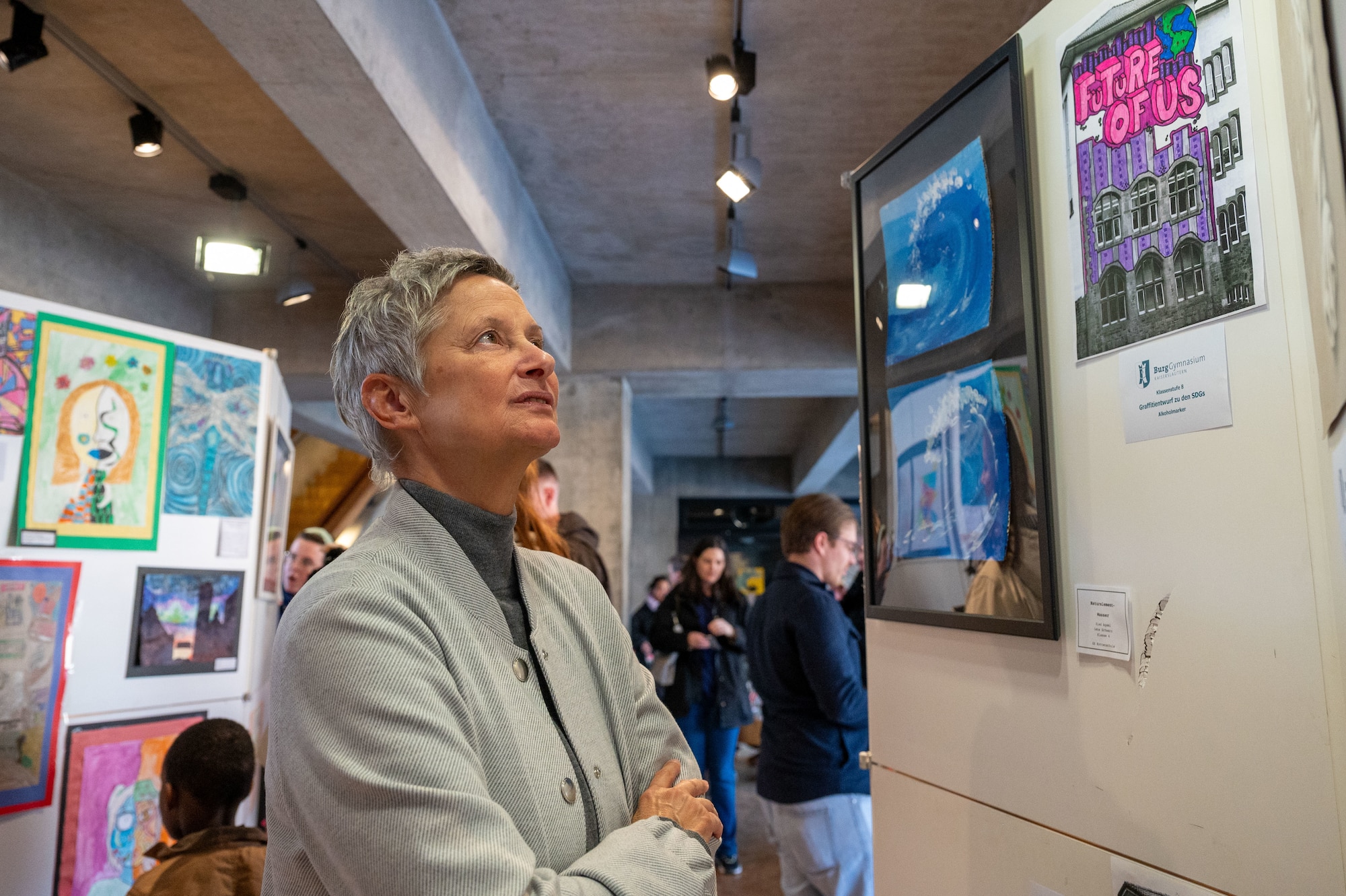 Beate Kimmel, Lord Mayor of Kaiserslautern, Germany, admires artwork at an art exhibition opening for the 22nd German American Community Office anniversary in Kaiserslautern, Germany, Feb. 18, 2025. This art exhibition signifies a continued partnership to bolster the GACO's mission of furthering communication and support within the Kaiserslautern community.