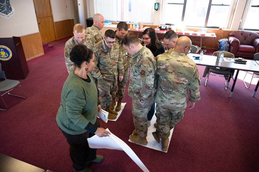 True North members participate in a team building exercise during the True North - Minot Installation Cohesion Meeting 2025 at the Northern Lights Chapel on Minot Air Force Base, North Dakota, Feb. 12, 2025. The team building activity, which involved participants fitting all their feet within gradually decreasing paper squares, demonstrated the importance of communication and adaptability. (U.S. Air Force photo by Senior Airman Kendra A. Ransum)