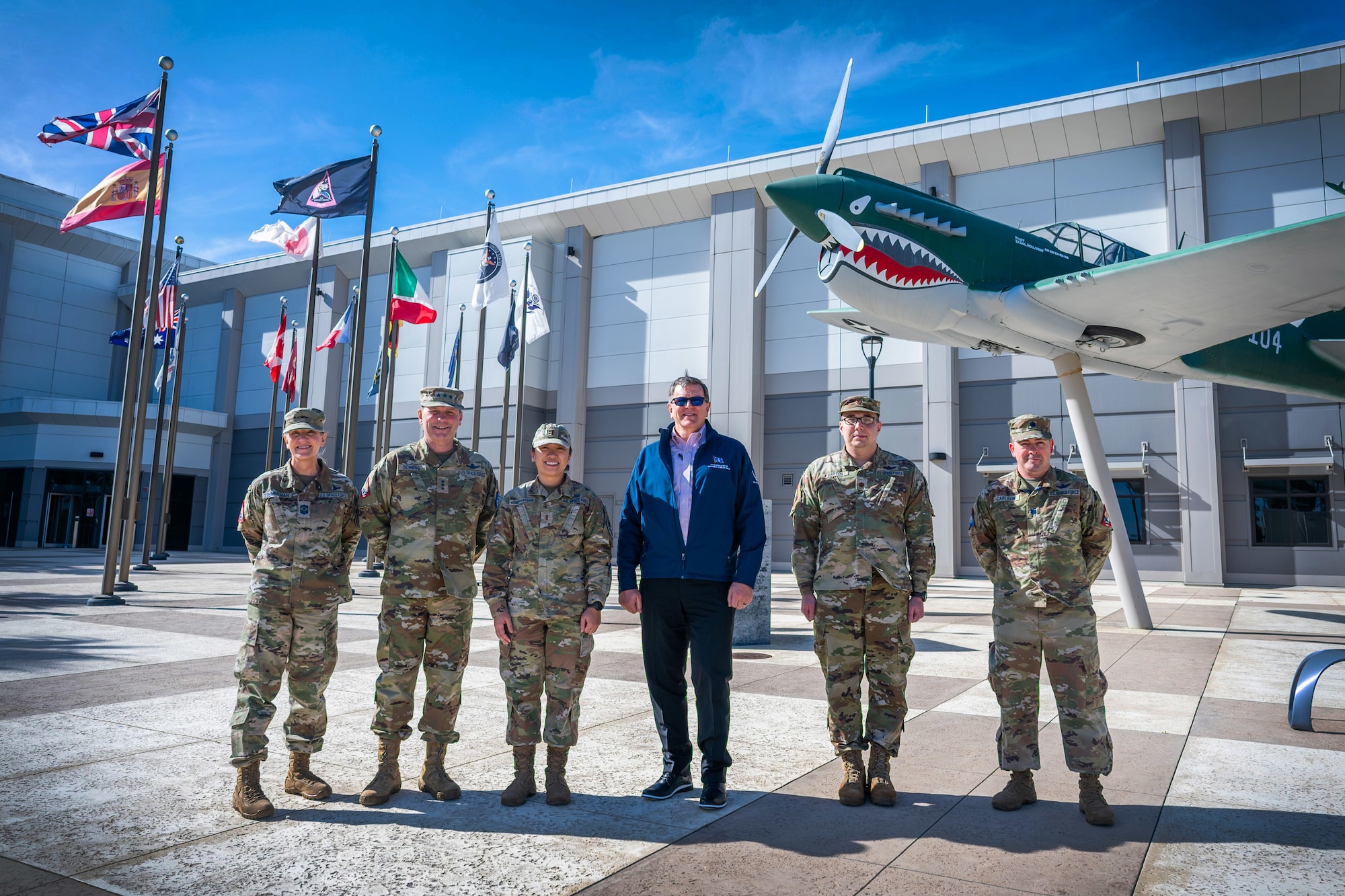 Military members stand together for a group photo outside in a courtyard.