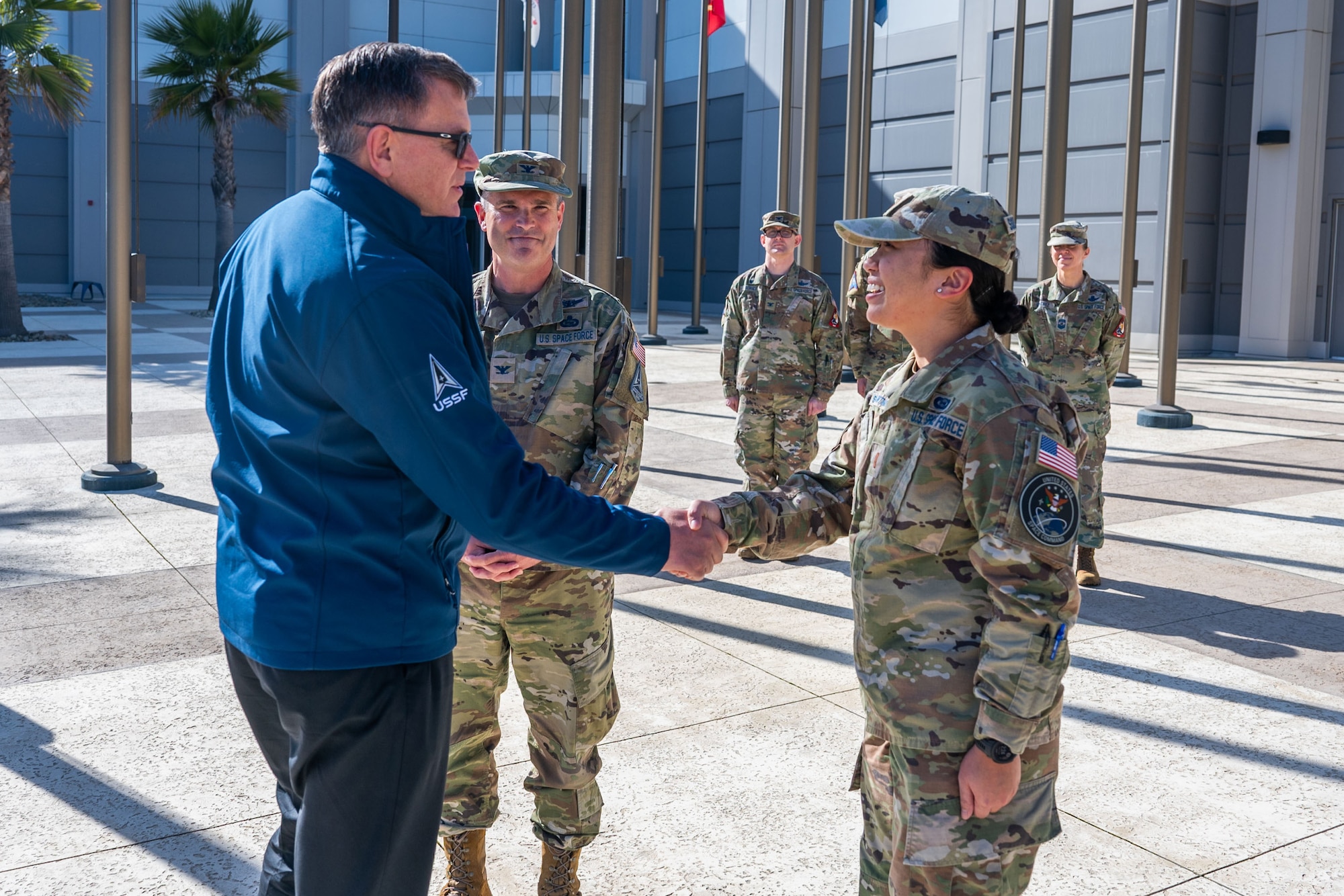 Military members in uniform talk outside in a courtyard.