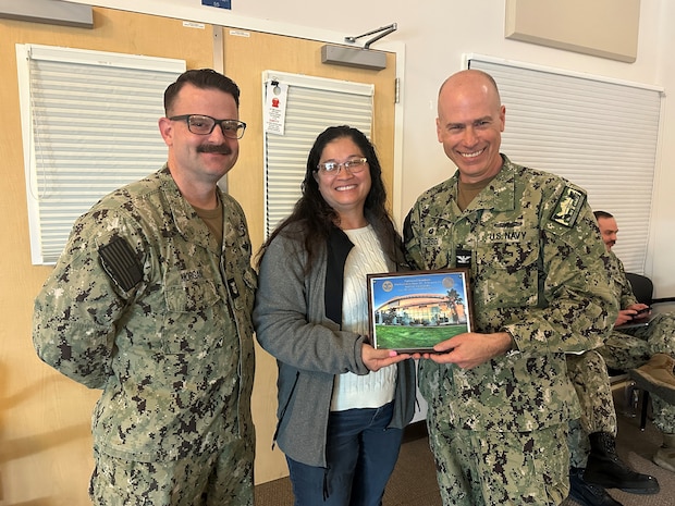 Capt. Aaron Werbel, commanding officer (right) of Navy Medicine Readiness and Training Command Lemoore and Command Master Chief Eric Morgan (left) bid farewell to Ombudsman Patricia Chambers (center) who was recognized for her service to the command with a plaque.  (U.S. Navy photo by Elaine Heirigs Naval Health Clinic Lemoore/Navy Medicine Readiness and Training Command Lemoore Public Affairs)
