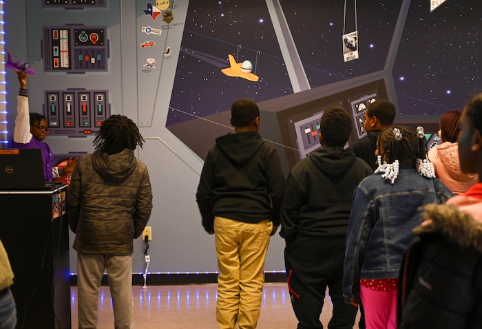 Students watch as a toy airplane zips down a string.