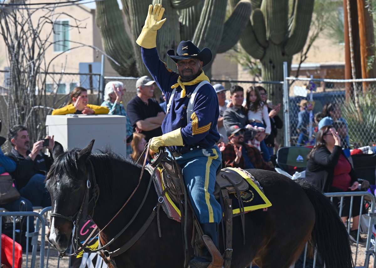 A historical U.S. military reenactor waves during the 100th Annual Tucson Rodeo Parade in Tucson, Arizona, Feb. 20, 2025. The parade featured over 130 entries, consisting of approximately 500 horses, 2,300 people, 85 wagons, 11 marching bands and service members from the 355th Wing. (U.S. Air Force photo by Staff Sgt. Abbey Rieves)