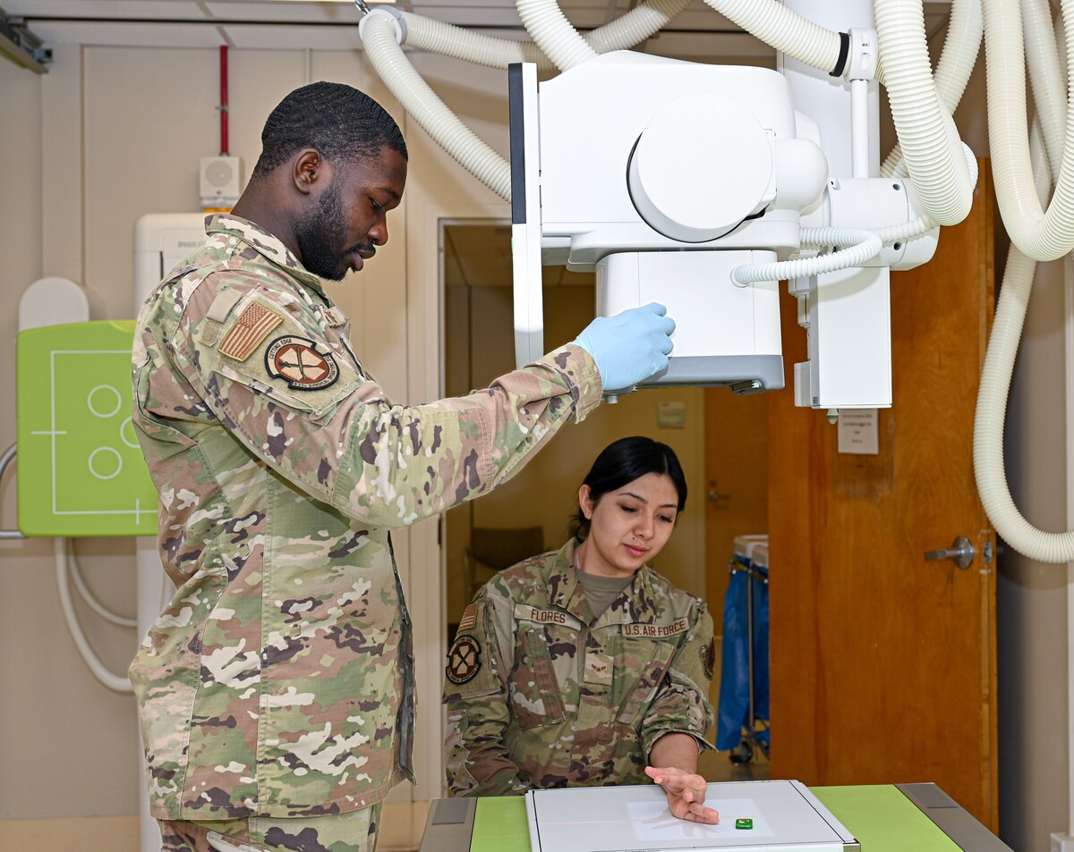 Airmen positioning an x-ray machine over a patient's hand.