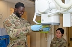Airmen positioned x-ray machine over patient's hand.