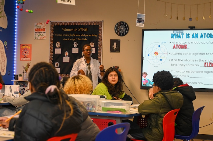 Students listen to a teacher talk about atoms