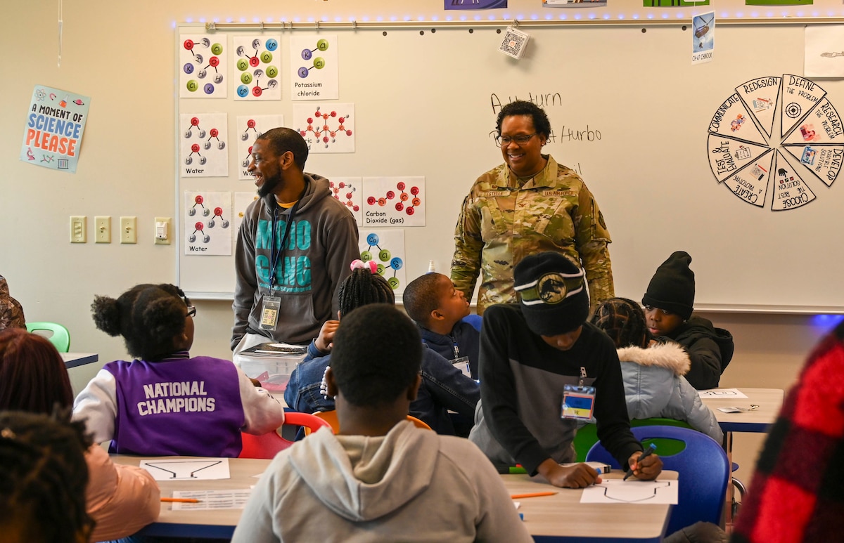 A service member interacts with students