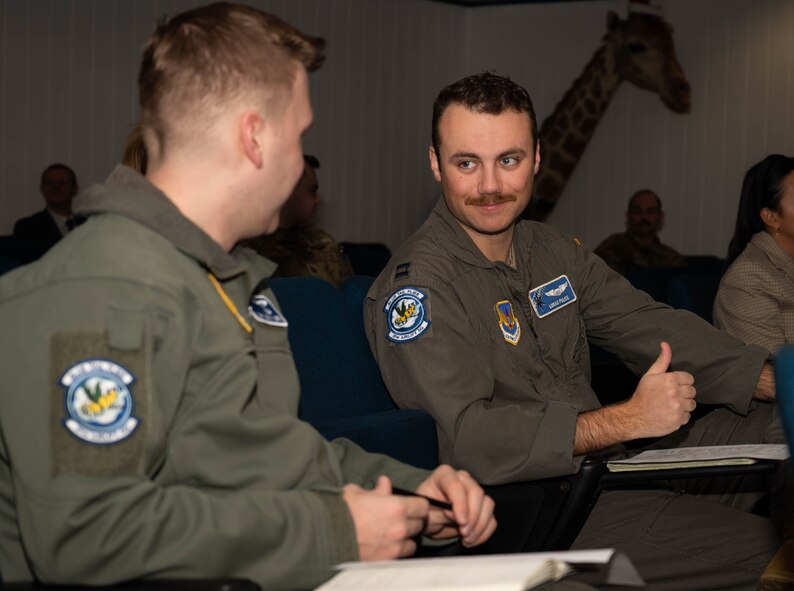 U.S. Air Force Capt. Johnny Murphy and  Capt. Lukas Pulice, 37th Airlift Squadron pilots, discuss mental health resources available to service members and their families of the Kaiserslautern Military Community during Military Aviator Peer Support wingman face-to-face training at Ramstein Air Base, Germany, Feb. 19, 2025. Participants of the training were recommended by their peers in the 86th OG to be part of the training because of their reputation of being supportive. The training enhanced their skills in listening to and supporting fellow Airmen needing help with life stressors. (U.S. Air Force photo by Senior Airman Jared Lovett)