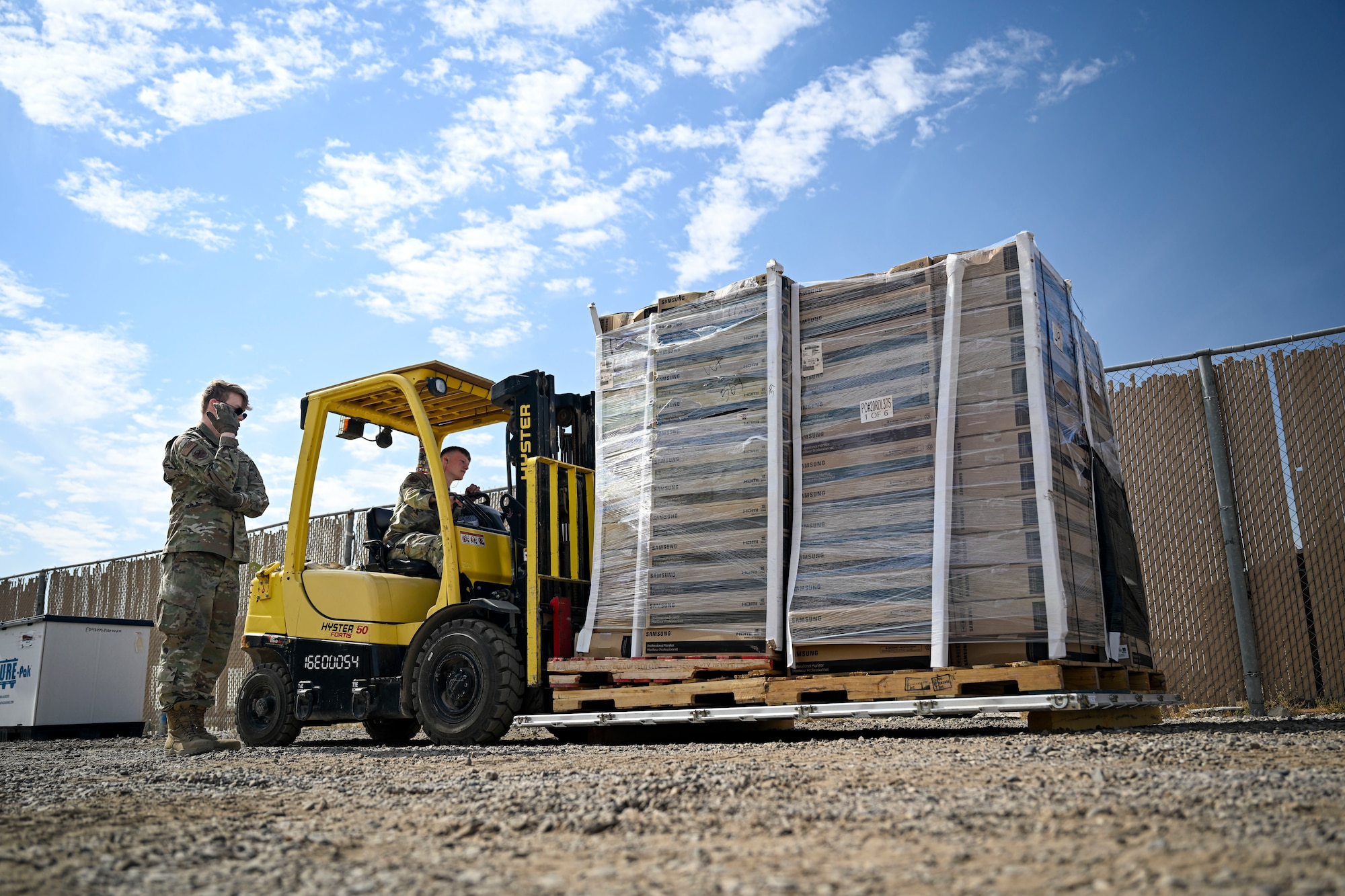 Two U.S. Air Force Airmen operates a forklift to move cargo.