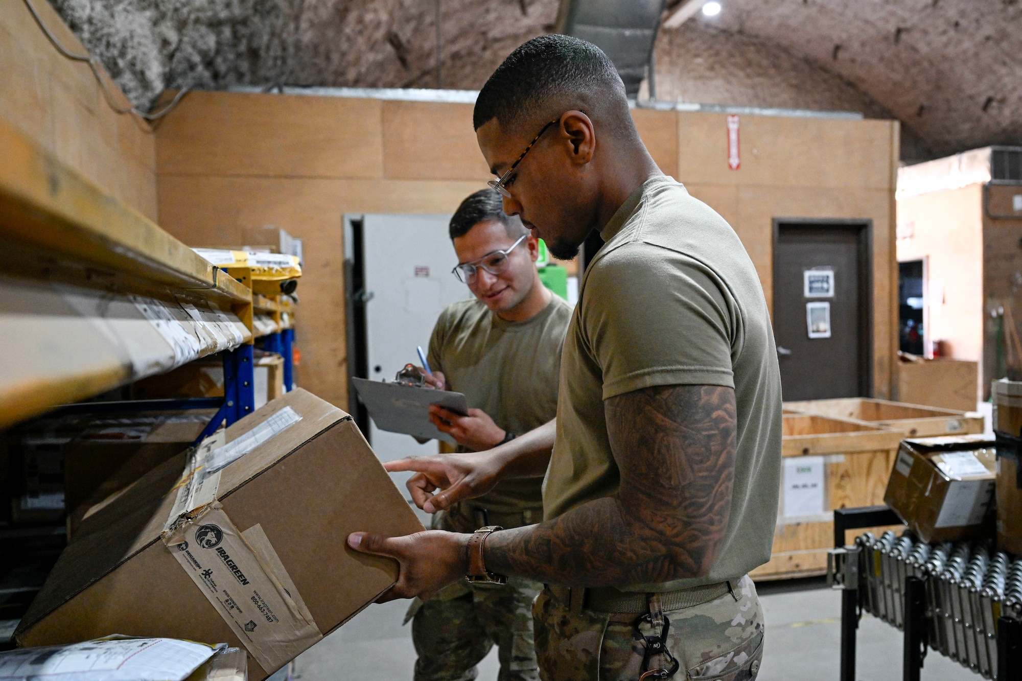 Two U.S. Air Force Senior Airmen conduct inventory inside.