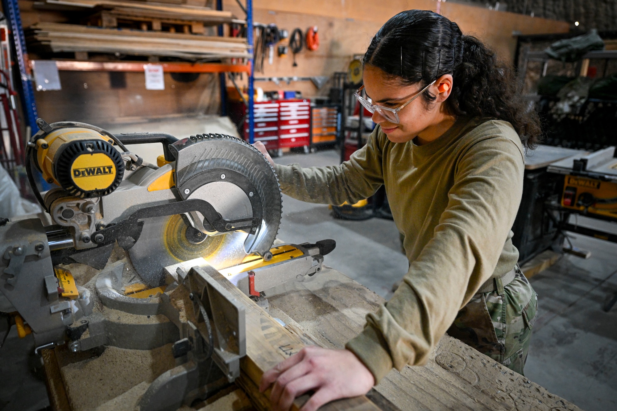 A U.S. Air Force Airman cuts a piece of wood.