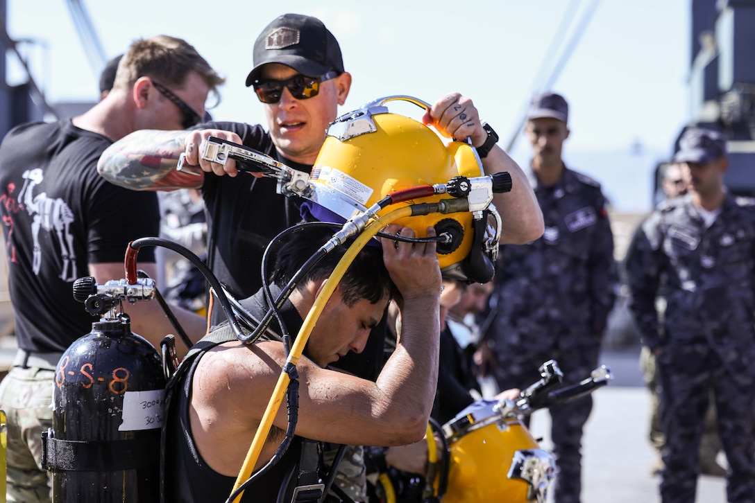 250212-A-WF586-1255 U.S. CENTRAL COMMAND AREA OF RESPONSIBILITY (Feb. 12, 2025) Chief Warrant Officer 2 Jordan Defarcy and Navy Diver 3rd Class Brandon Ibarra, both assigned to Commander, Task Group (CTG) 56.1, demonstrate removal of equipment for surface supplied dive training during International Maritime Exercise (IMX) 2025. IMX25 is the largest multinational training event in the Middle East, involving 5,000 personnel from around 30 nations and international organizations committed to preserving the rules-based international order and strengthening regional maritime security cooperation. (U.S. Army photo by Sgt. Thomas Brown)