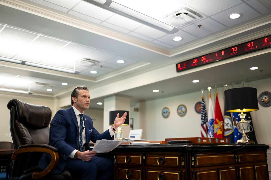 Defense Secretary Pete Hegseth delivers remarks while seated in an office.