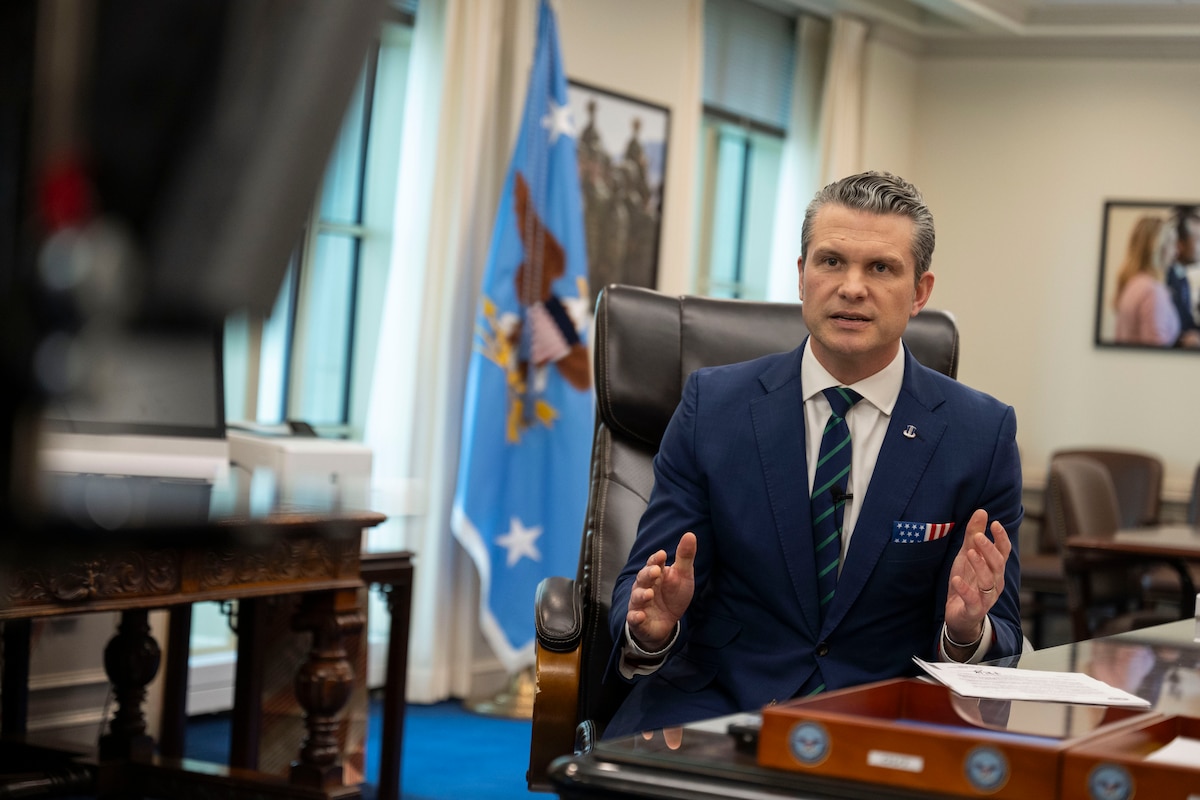 Defense Secretary Pete Hegseth delivers remarks while seated in an office.