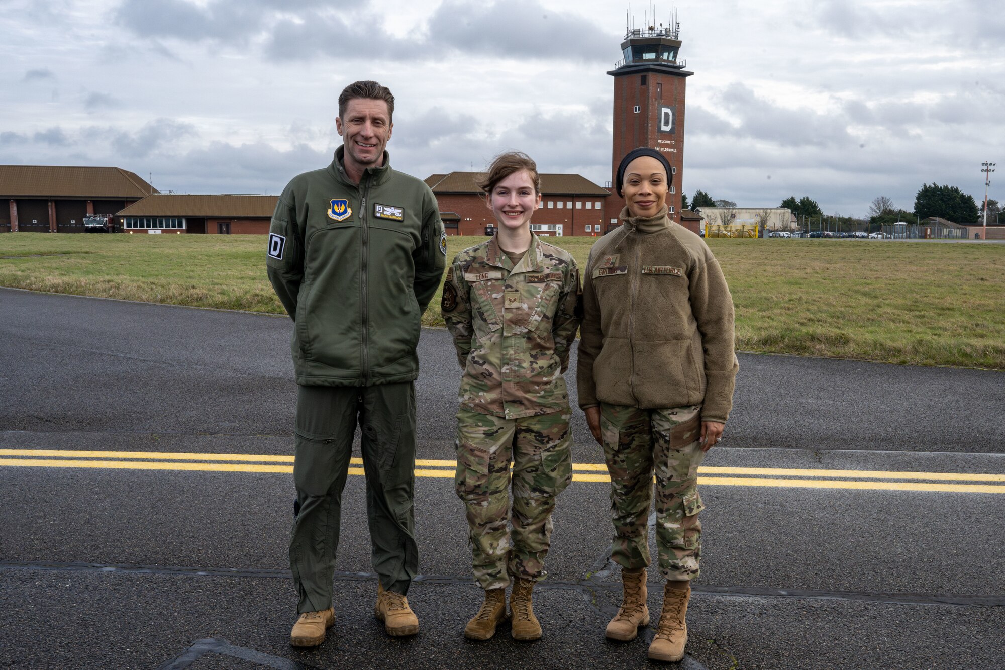 U.S. Air Force Col. Ryan Garlow, left, 100th Air Refueling Wing commander, Senior Airman Elizabeth Long, center, 100th Operations Support Squadron airfield management shift lead, and Chief Master Sgt. Tiffany Griego, 100th ARW command chief, pose for a photo after a “Day in the Life” integration with the 100th OSS at RAF Mildenhall, England, Feb. 21, 2025.
