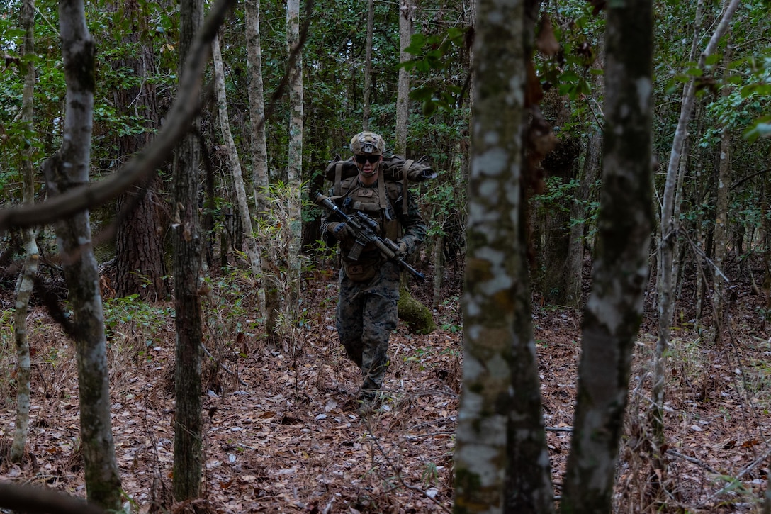 U.S. Marine Corps Lance Cpl. Justin Jensen, a machine gunner with Lima Company, Battalion Landing Team, 3rd Battalion, 6th Marine Regiment, 22nd Marine Expeditionary Unit, patrols through terrain during a simulated raid in support of Marine Air Ground Task Force (MAGTF) Interoperability Exercise at Stone Bay on Marine Corps Base Camp Lejeune, Feb. 10, 2025. The raid is one of several training events within the Marine Air Ground Task Force Interoperability, a course conducted by Expeditionary Operations Training Group. This course is designed to train and evaluate integrated elements of the 22nd MEU across a variety of full mission profiles in a simulated peer threat environment. (U.S. Marine Corps photo by Cpl. Emily Hazelbaker)
