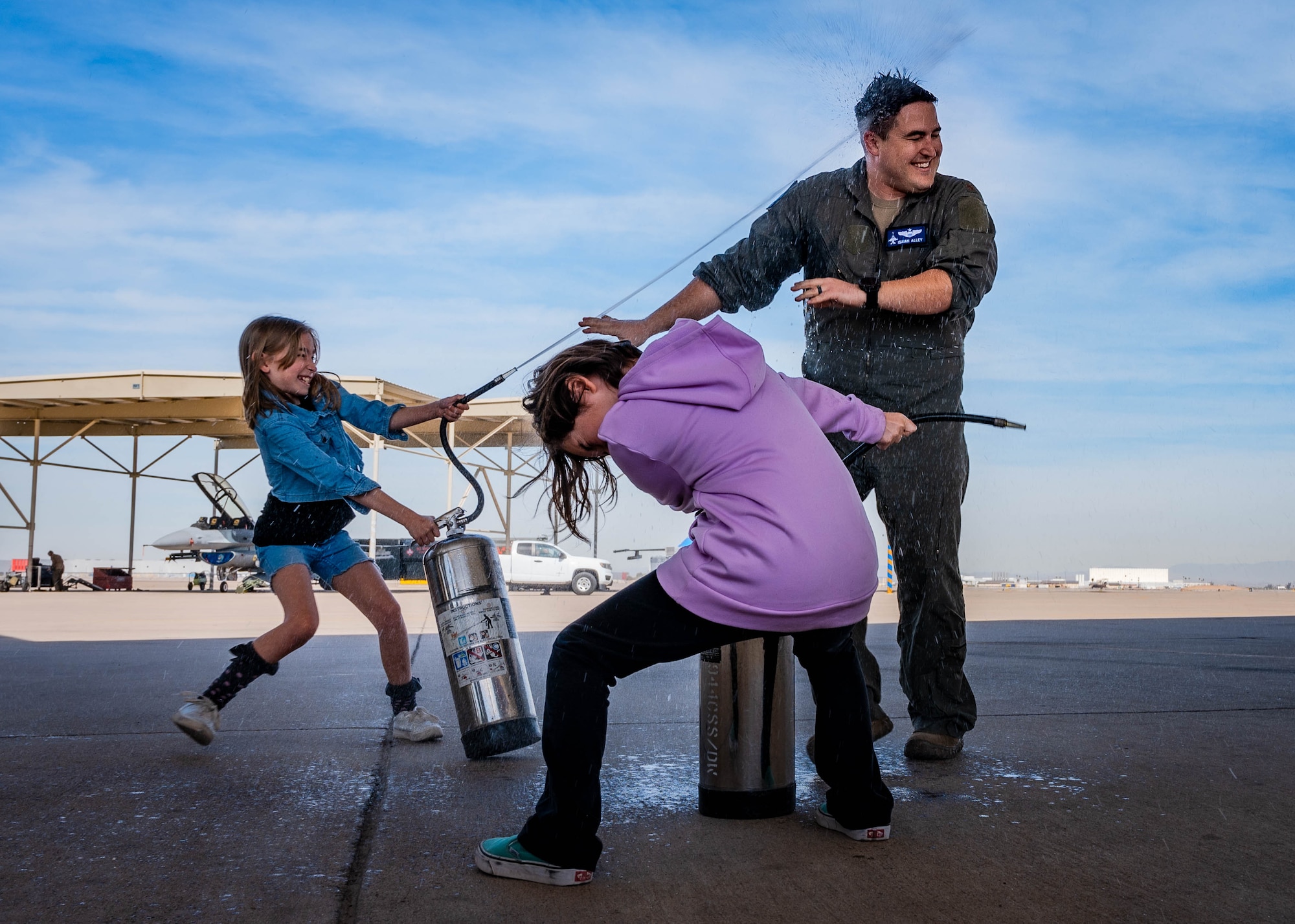 U.S. Air Force Maj. Isaiah Alley, 309th Fighter Squadron director of operations, is greeted with a celebratory spray of water from his daughter and niece.