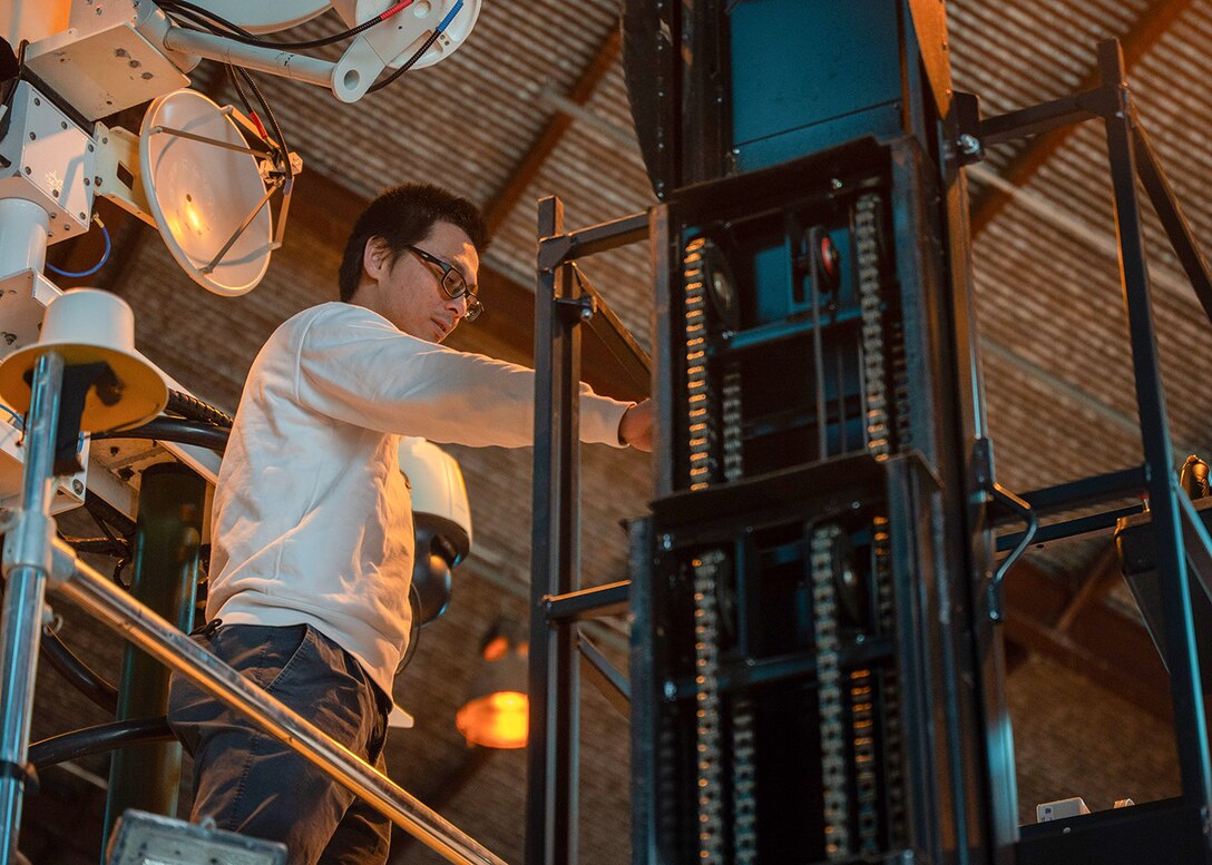 A man looks at the basket on a forklift used to safely lift people to work on items safer than working on a ladder