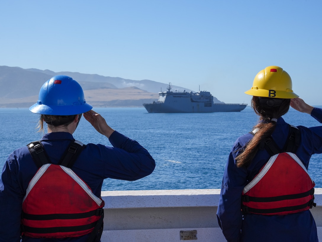 Coast Guard Petty Officer Brooklyn Baker and Seaman Calista Turman salute to render honors as the Royal New Zealand Navy ship Canterbury (L421) passes the Coast Guard Cutter Midgett (WMSL 757) in Wellington Harbour, New Zealand, Feb. 14, 2025. The Coast Guard continues to build on the Memorandum of Agreement signed with the Royal New Zealand Navy in 2023 allowing both nations to share experiences and knowledge to cultivate best practices and support maritime governance. (U.S. Coast Guard photo by Petty Officer 3rd Class Jennifer Nilson)