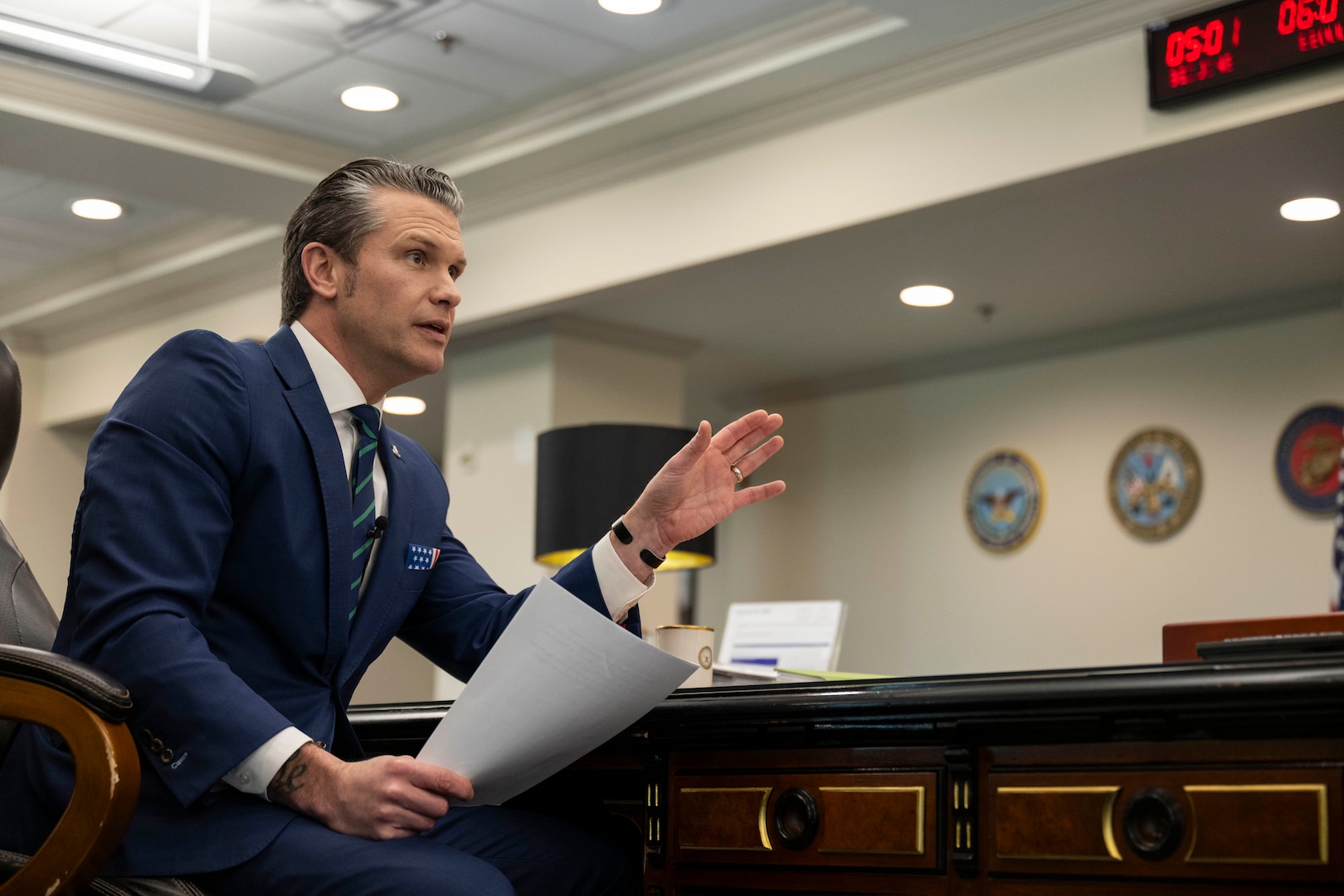 Defense Secretary Pete Hegseth delivers remarks while seated in an office.