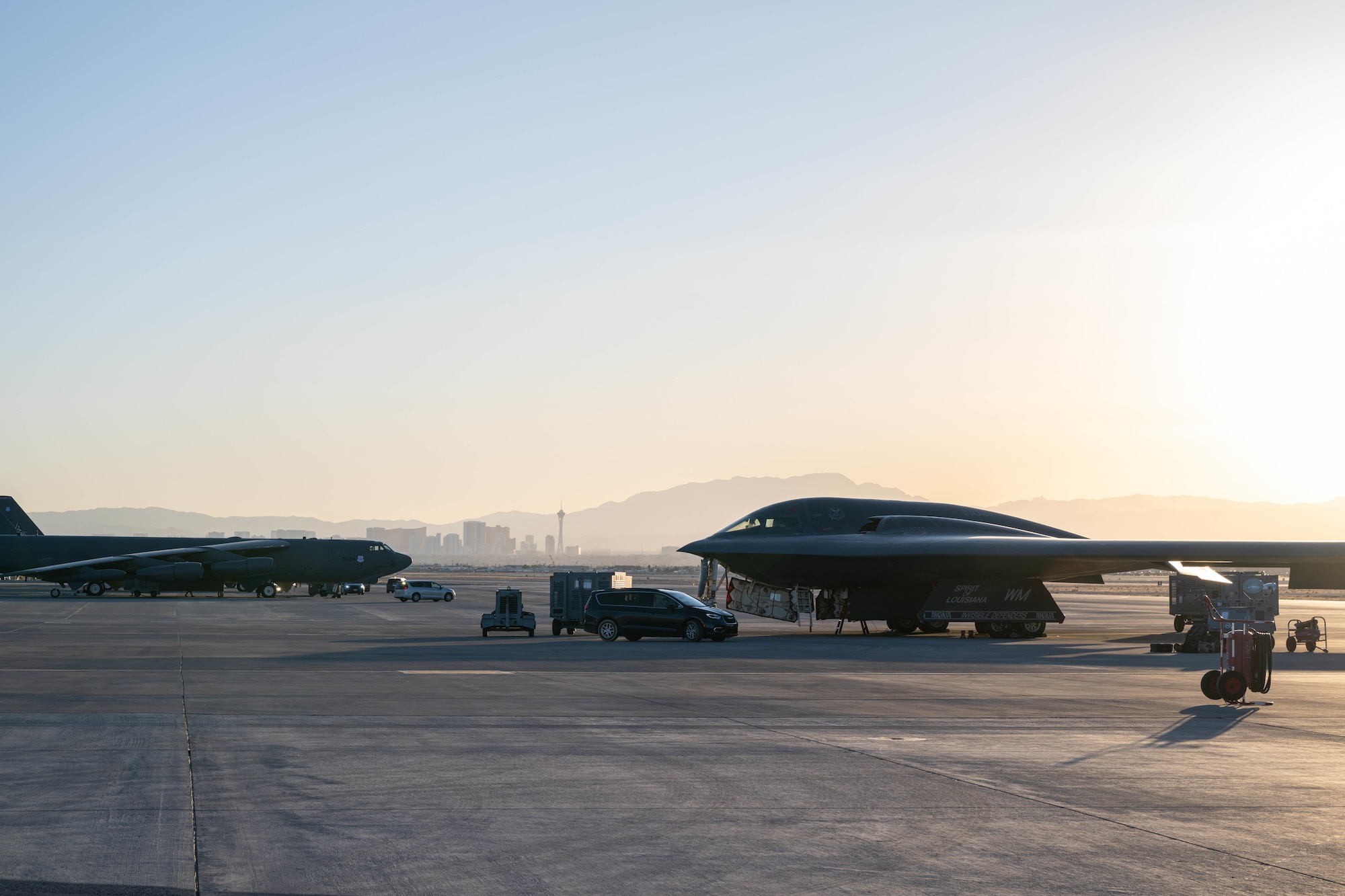 A B-2 Spirit stealth bomber and a B-52 bomber sit on the Nellis Air Force Base flight line during exercise Bamboo Eagle on Nellis Air Force Base Feb. 10, 2025. Bamboo Eagle provides a realistic training environment to test and refine bomber force tactics, techniques, and procedures. (U.S. Air Force photo by Senior Airman Bryson Sherard)