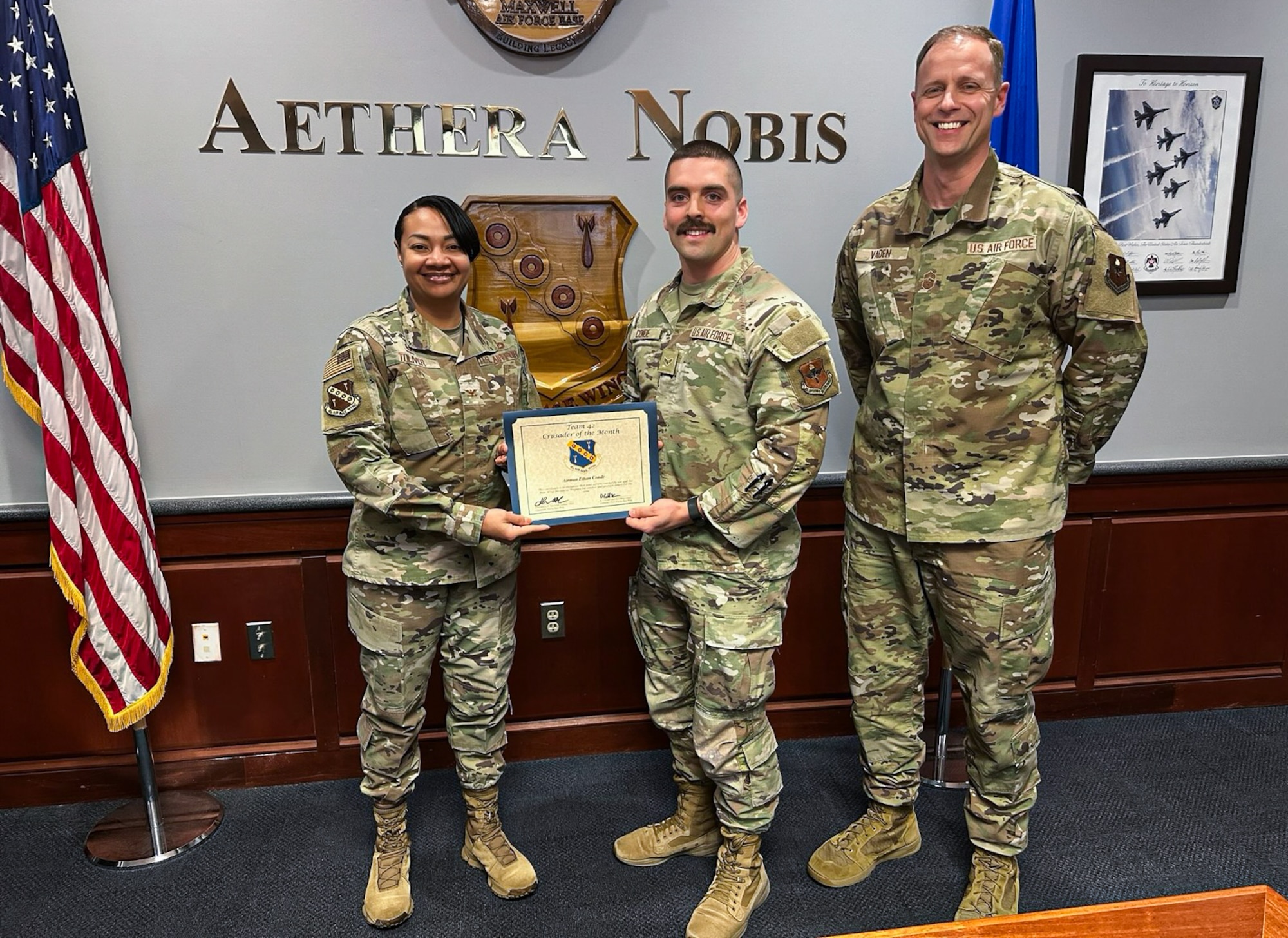U.S. Air Force Airman 1st Class Ethan Conde, 42nd Communication Squadron client system technician, received the Crusader of the Month award from Col. Shamekia Toliver, left, 42nd Air Base Wing commander, and Chief Master Sgt. Caleb Vaden, 42nd ABW command chief at Maxwell Air Force Base, Alabama, Jan. 29, 2025.