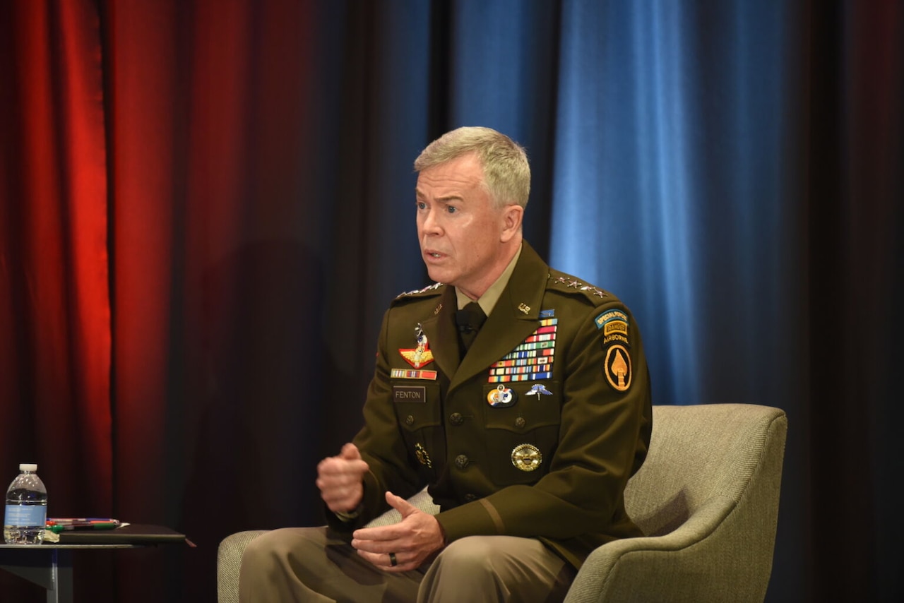 A soldier on stage sits in a chair as he speaks.